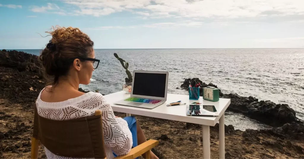 A freelance working on a laptop with a beach view, representing a flexible work-from-anywhere lifestyle.