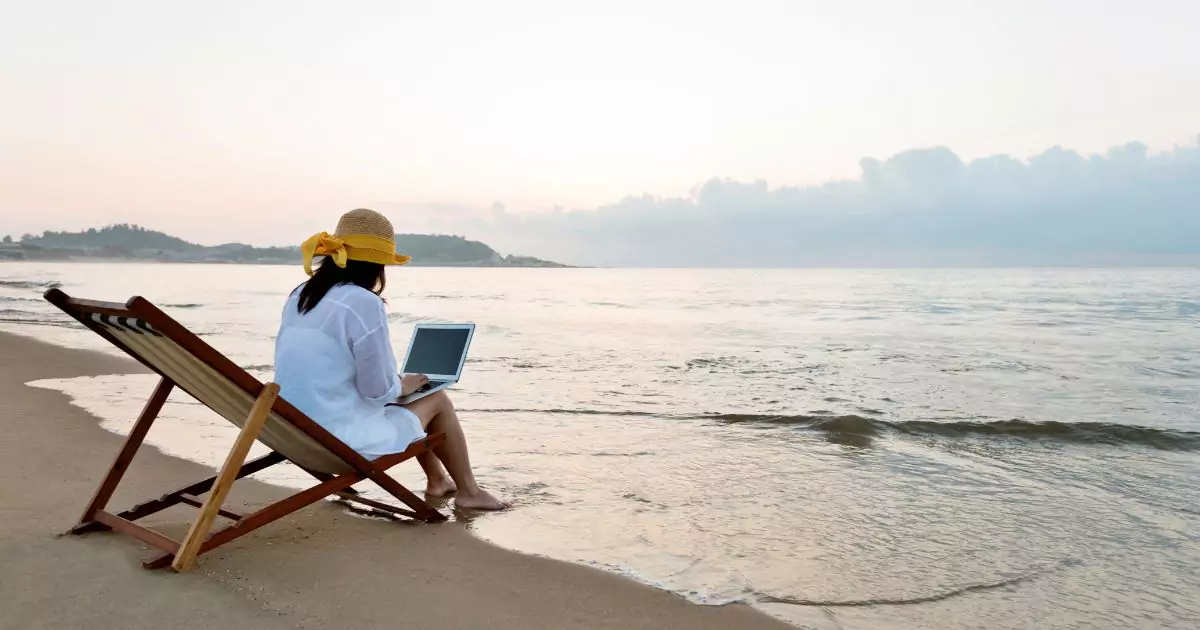 A woman seated in a beach chair, working on her laptop while enjoying the serene beach environment.