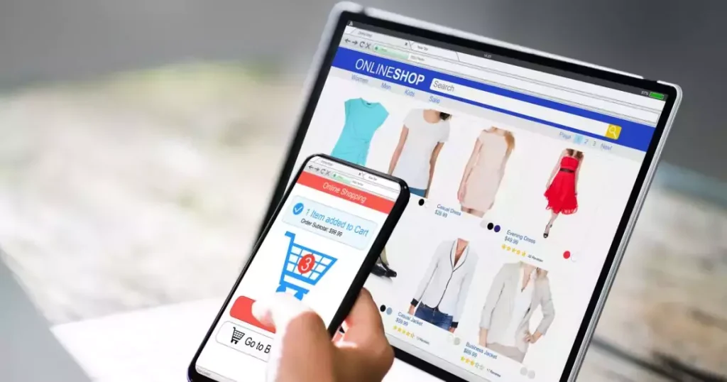 A person shopping online on a smartphone and laptop, browsing clothing items with a shopping cart notification visible.