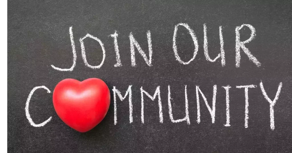 White chalk writing on a blackboard reads “Join Our Community,” accompanied by a red heart, symbolizing love and connection.