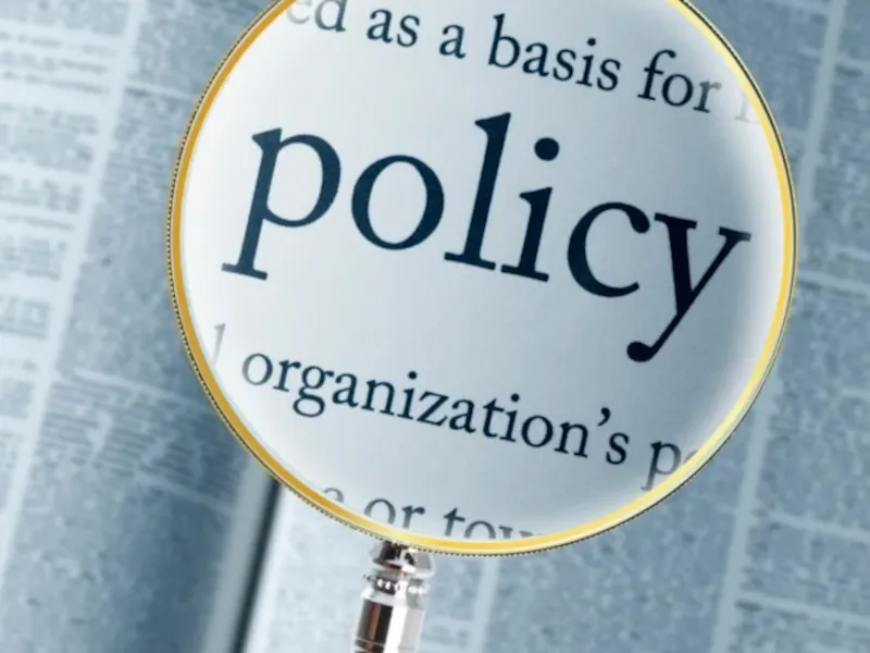 This privacy policy guide is symbolized by a close-up of a magnifying glass highlighting the word 'policy' on a document, emphasizing its critical role in organizational transparency and compliance.