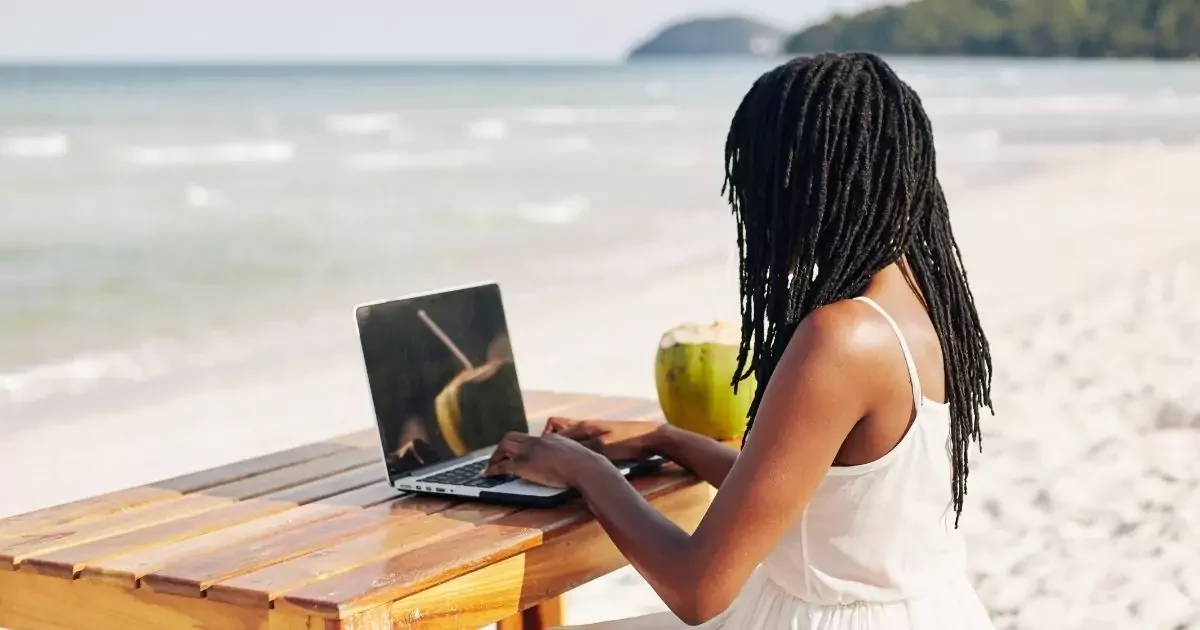 A Freelancer is working on a laptop with a beach view, representing a flexible work-from-anywhere lifestyle.