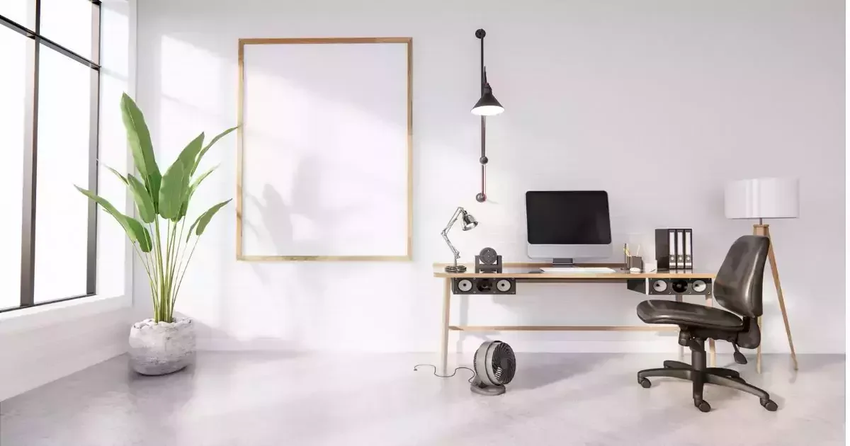 A modern home office featuring a desk with a computer, a task lamp, potted plant, and ergonomic chair against a bright, minimalistic backdrop.